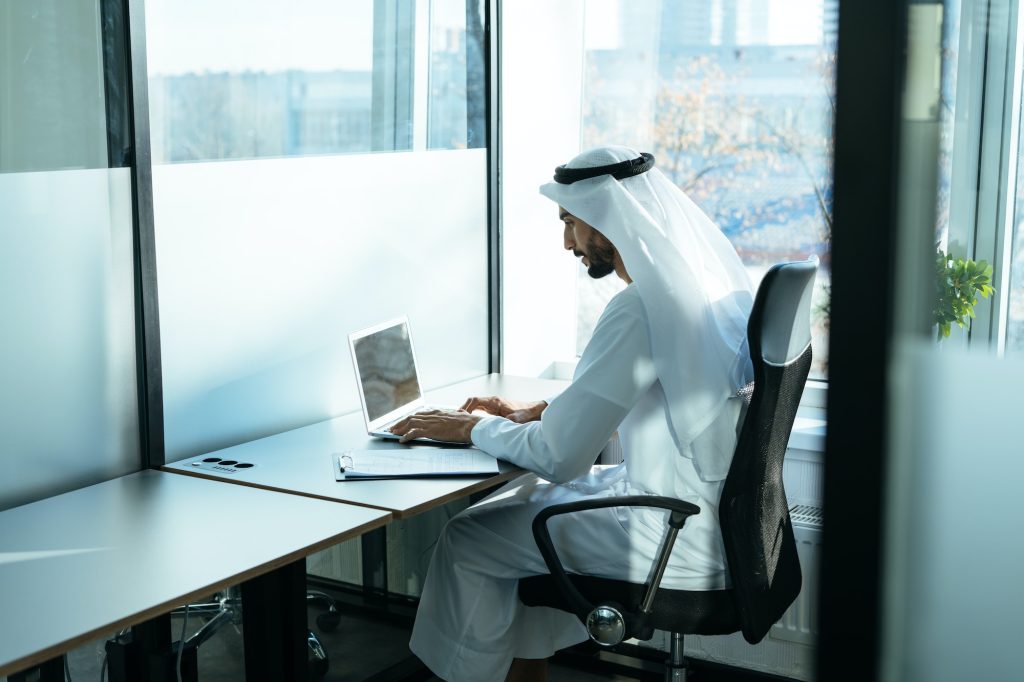 handsome man with traditional clothes working in an office of Dubai