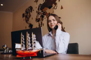 Young female travel agent consultant in tour agency phone call
